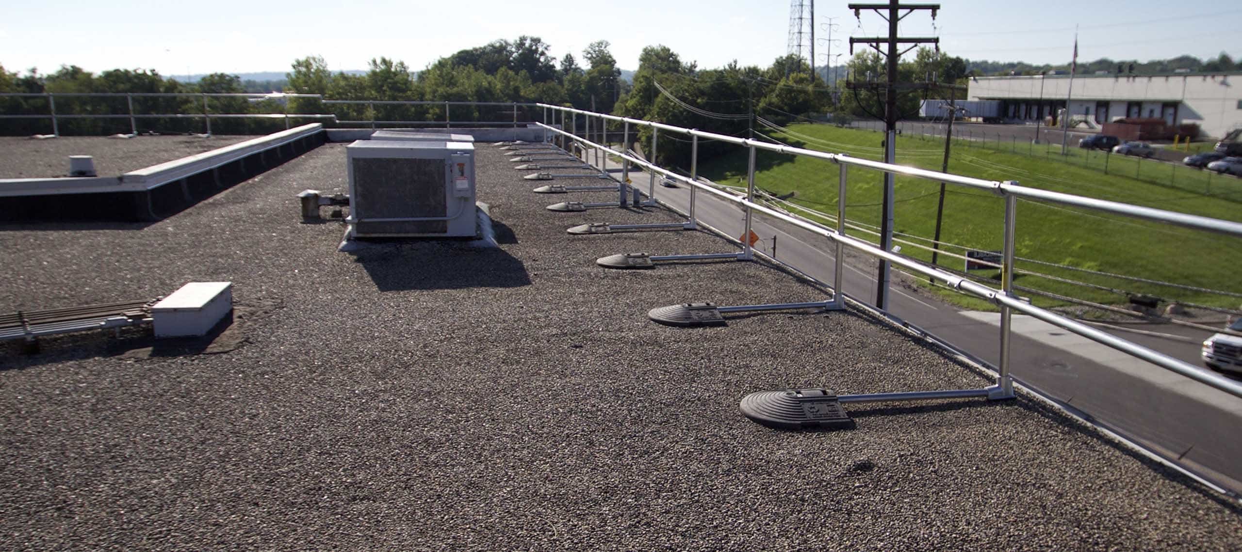 Rooftop unit near a roof edge protected by non-penetrating KeeGuard guardrail